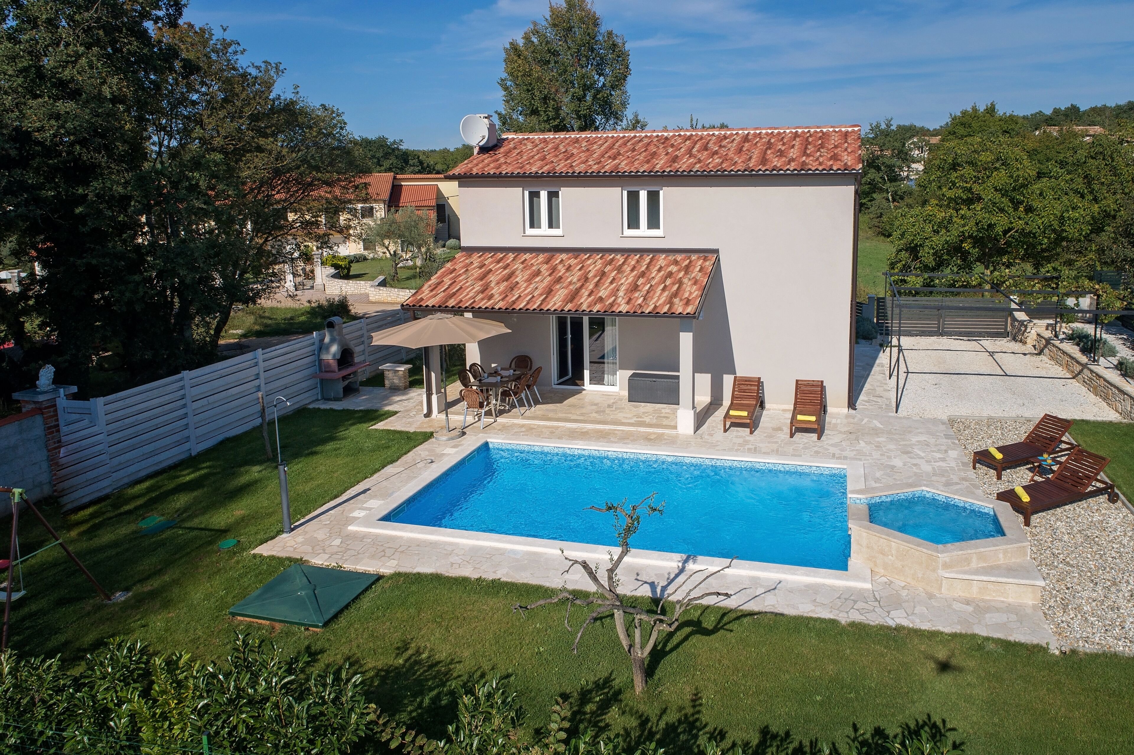 Une maison à deux étages avec une piscine, une terrasse avec des chaises et une cour clôturée.