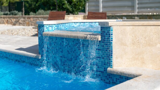 A swimming pool with clear blue water and a tiled edge.