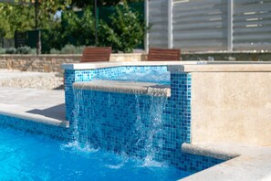 A swimming pool with clear blue water and a tiled edge.