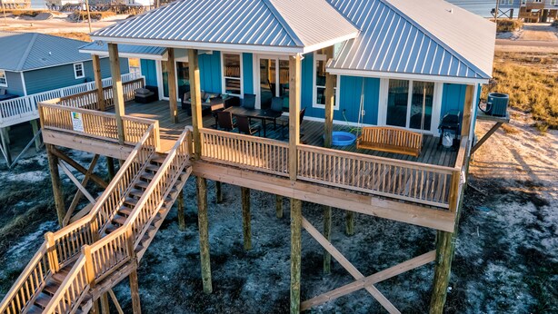 Een huis aan het strand met een terras en een zitgedeelte buiten.