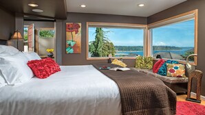 Une chambre avec un grand lit, une vue sur la montagne et l’eau, et une fenêtre offrant un beau panorama.
