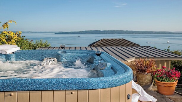 Un jacuzzi avec vue sur la mer et une maison en arrière-plan.