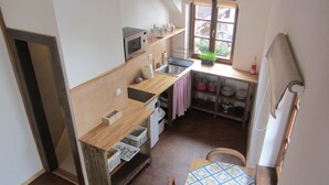 A compact kitchen with a microwave, sink, and wooden counter. - Willow apartment at Kamenný potok (Kájov)