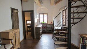 A spacious living area with a spiral staircase, wooden furniture, and a view into the kitchen. - Willow apartment at Kamenný potok (Kájov)