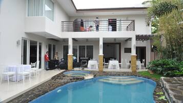 Un área de piscina con diferentes opciones de asientos y un porche cubierto.