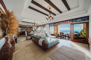 Een ruime woonkamer met een bank, een eettafel en uitzicht op de oceaan.