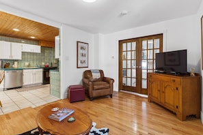 A living room with a wooden floor, a brown leather chair, a wooden cabinet, and a television.