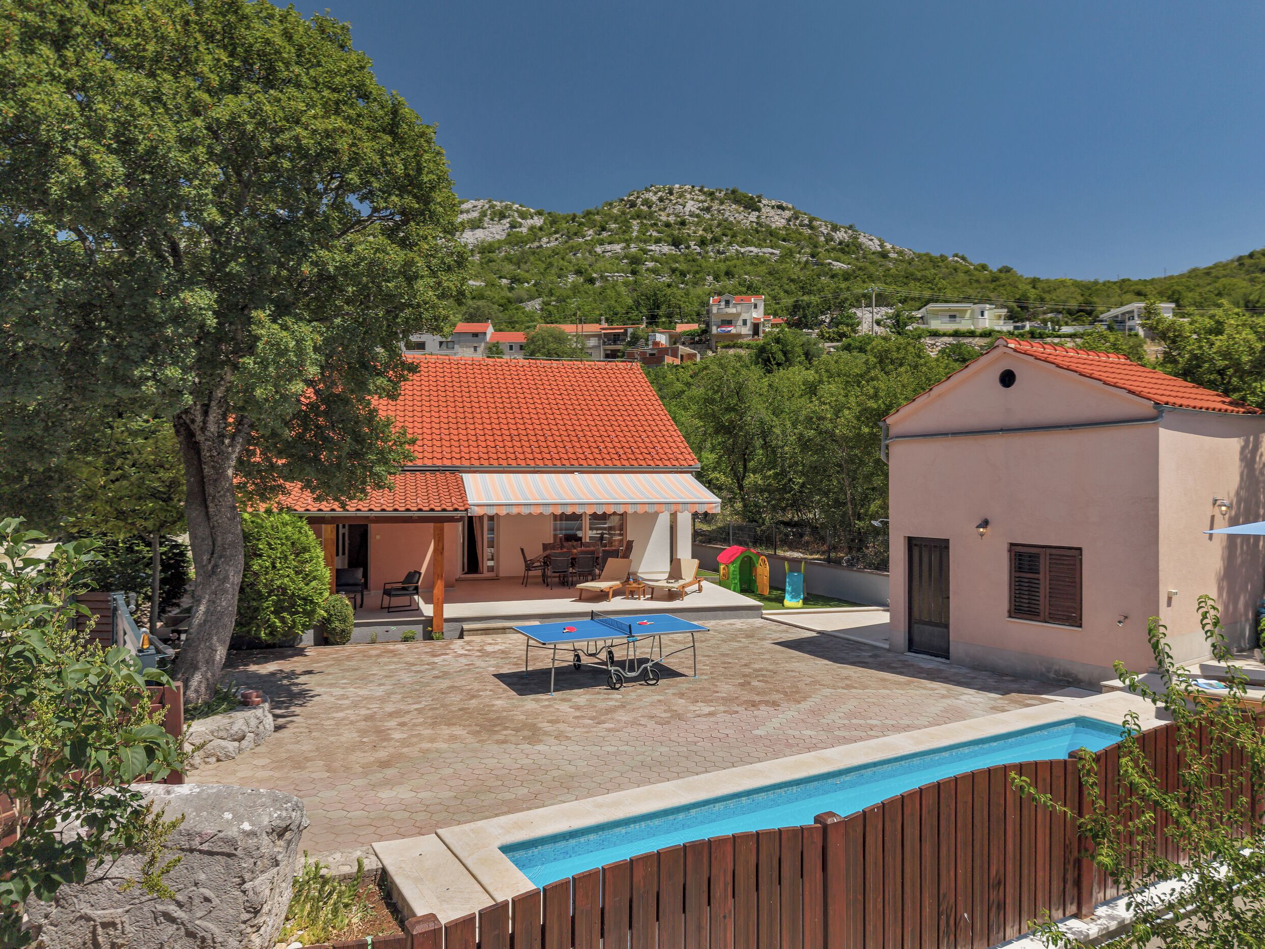 Ein Wohngebiet mit Schwimmbad, überdachter Terrasse und Blick auf eine Hügelkette.