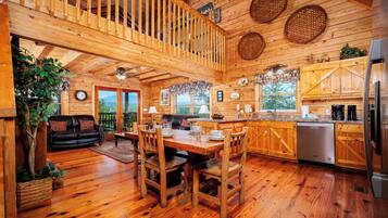 A wooden cabin interior with a dining area, kitchen, and a balcony with wicker baskets.