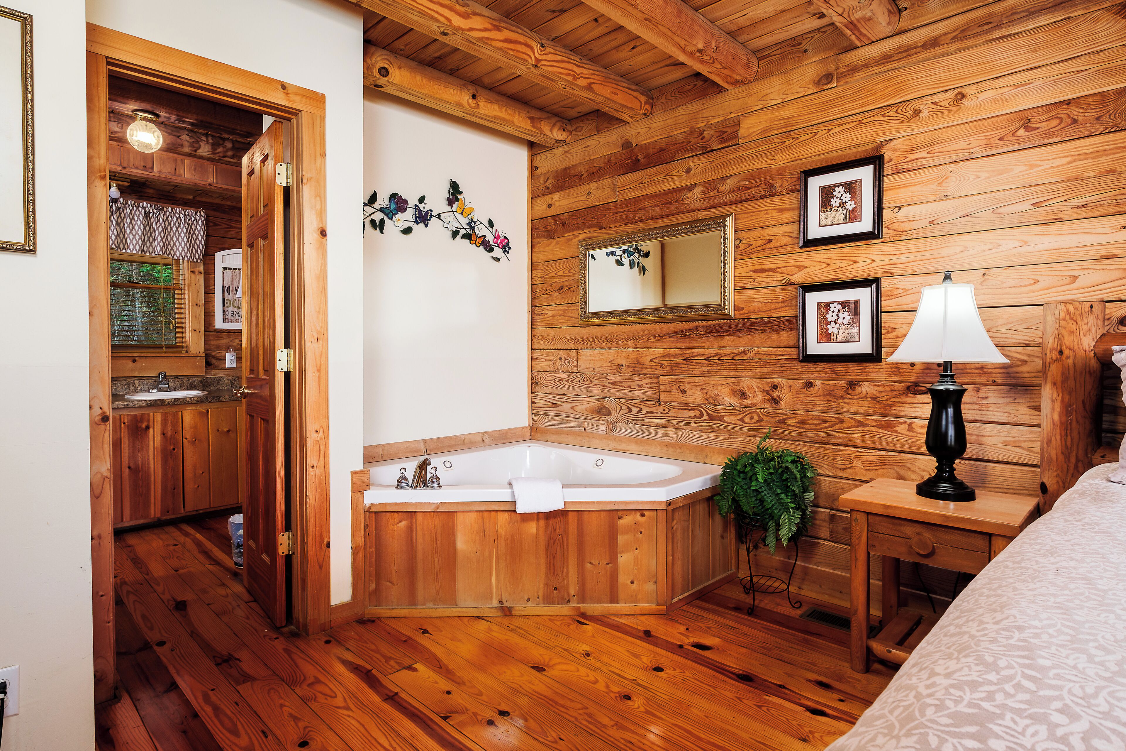 A wooden cabin interior with a bathroom featuring a wooden bathtub, a sink, and a mirror.