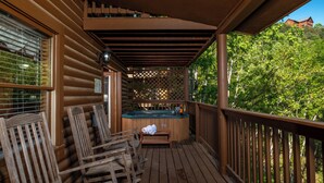 Une terrasse en bois avec un jacuzzi, des chaises en bois et une clôture en bois.