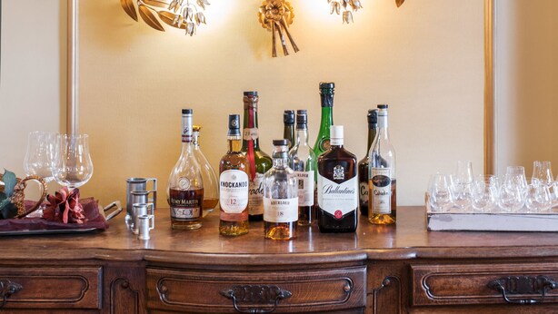 Un espace bar agrémenté d’un mur décoratif, ainsi que d’une variété de bouteilles d’alcool et de verres.