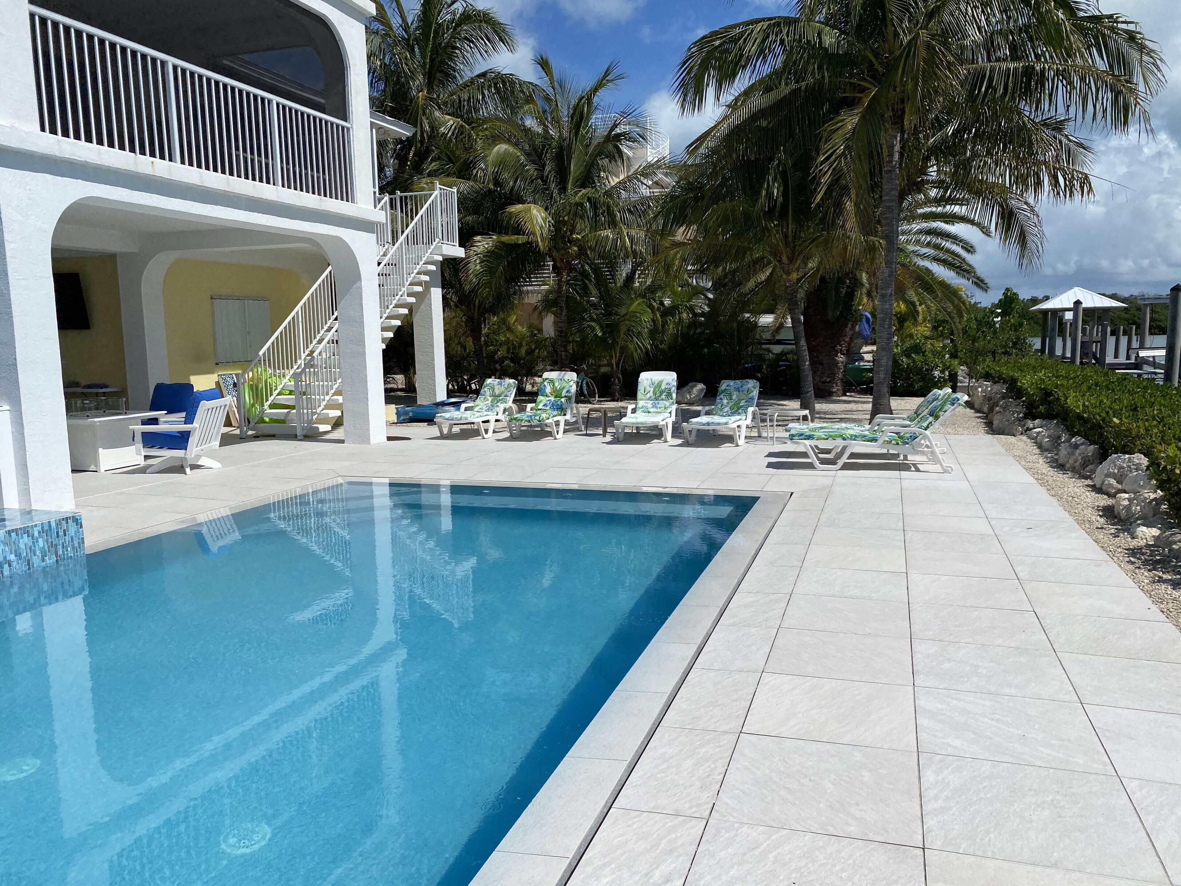 Une piscine avec des chaises longues et un escalier menant à un balcon.