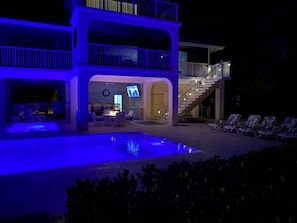 A two-story building with a pool, outdoor seating, and a staircase leading to a balcony.