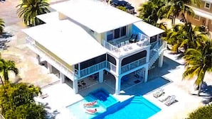 A two-story building with a swimming pool, balconies, and palm trees. - Outstanding pool and outdoor area 5 minute walk to beach! (Marathon)