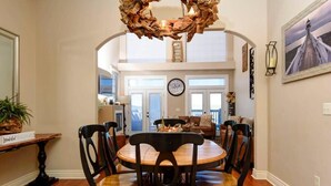 Un'area pranzo con un tavolo rotondo in legno e sedie, una ghirlanda decorativa appesa sopra e un orologio sul muro.