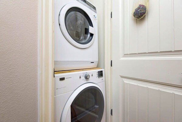 Une buanderie équipée de deux machines à laver superposées et d’un étendoir à linge.