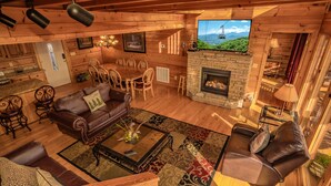 A cozy log cabin interior with a fireplace, wooden furniture, and a television displaying a scenic view. - A Home For The Starrs: Spectacular Views! Resort Pool. Got it all. Near Dollywood and Pigeon Forge! (Sevierville)