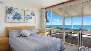 A bedroom with a large bed, a nightstand, a lamp, and two abstract paintings. - Sand Castles - 34 Gold Coast Drive (CARRICKALINGA)