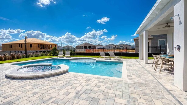 Una piscina con sillas de descanso, un jacuzzi y un patio con mesa y sillas.