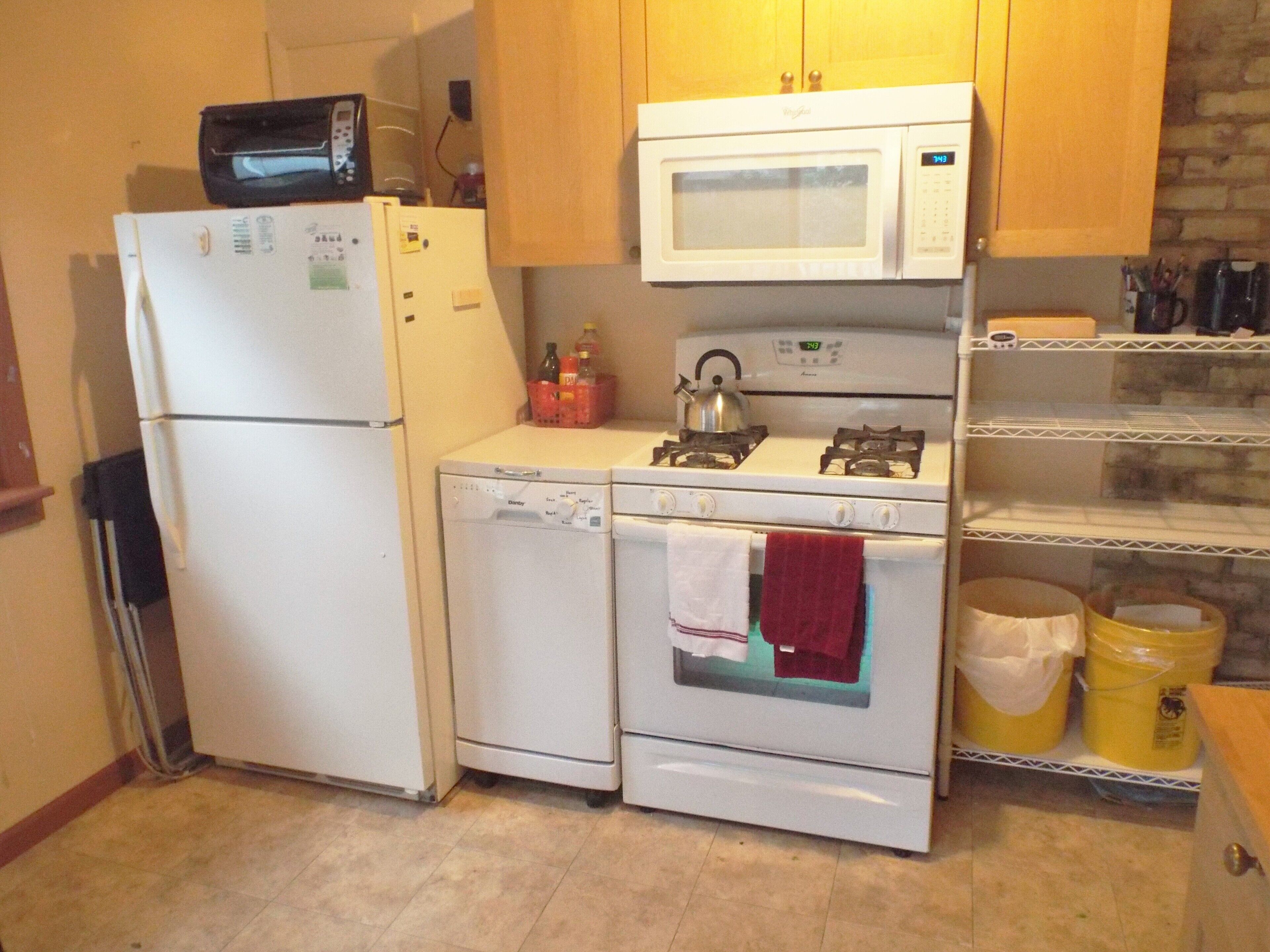 A compact kitchen with a refrigerator, microwave, stove, and oven.