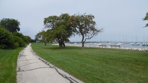 A pathway leading to a grassy area with trees and a view of boats in the distance. - Comfortable 3BR Craftsman Bungalow in Milwaukee Bay View Neighborhood Sm Dog OK (Milwaukee)