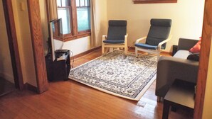 A room with two chairs, a small rug, wooden flooring, and a window. - Comfortable 3BR Craftsman Bungalow in Milwaukee Bay View Neighborhood Sm Dog OK (Milwaukee)