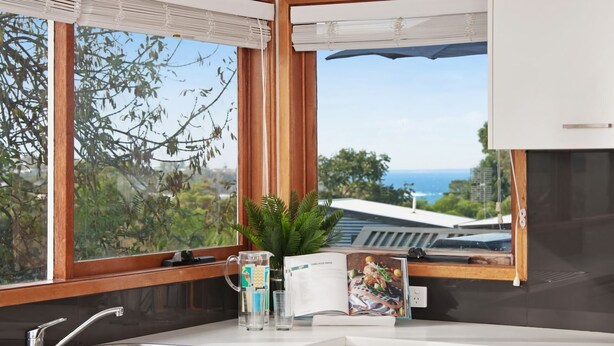 Une cuisine avec vue sur la mer, une plante, un magazine et une tasse à café.