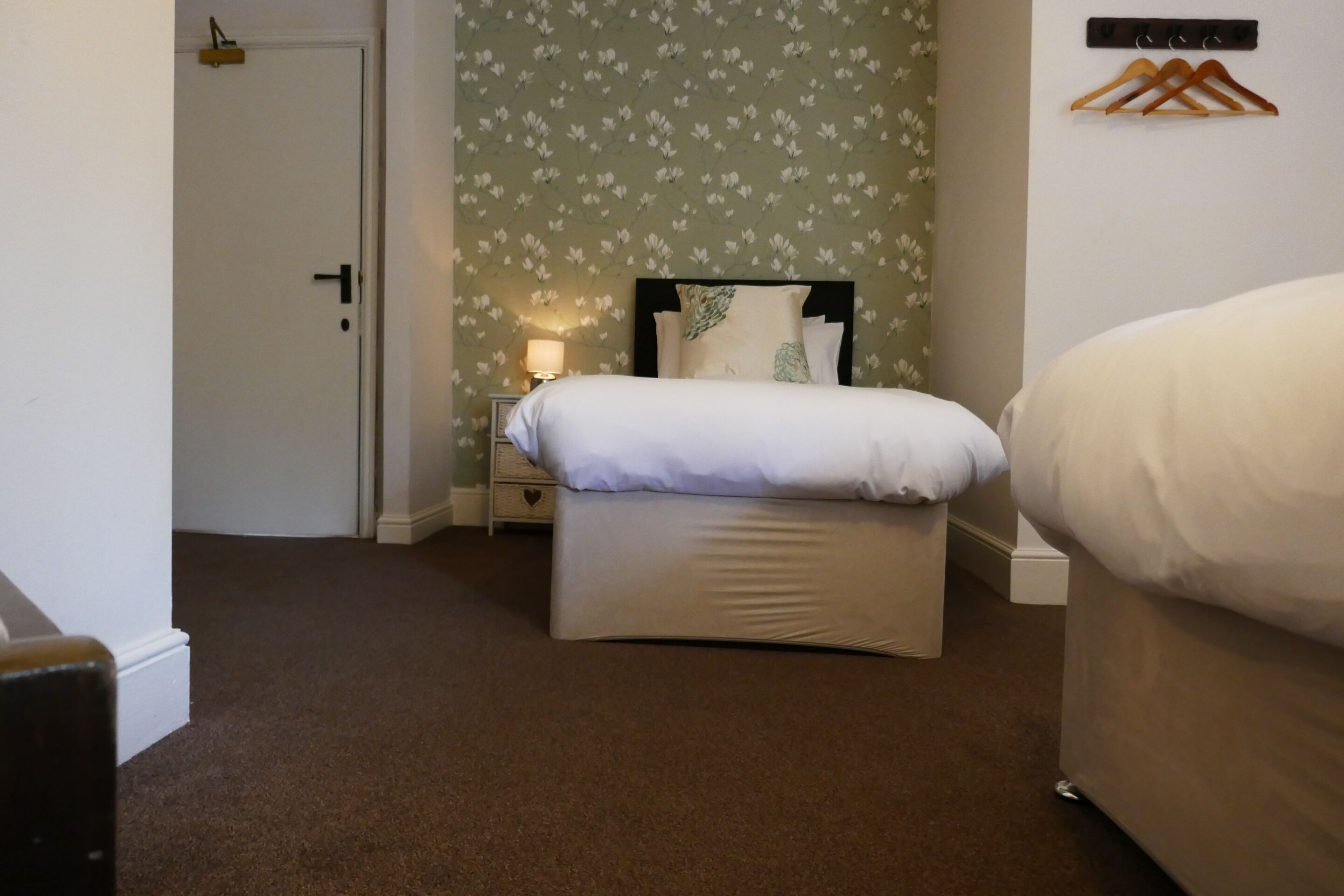 A bedroom with a bed, a nightstand, a dresser, and a door.
