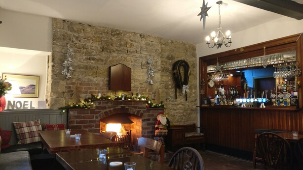 A cozy pub with a stone fireplace, wooden bar, and comfortable seating. - The Victoria (Skipton)