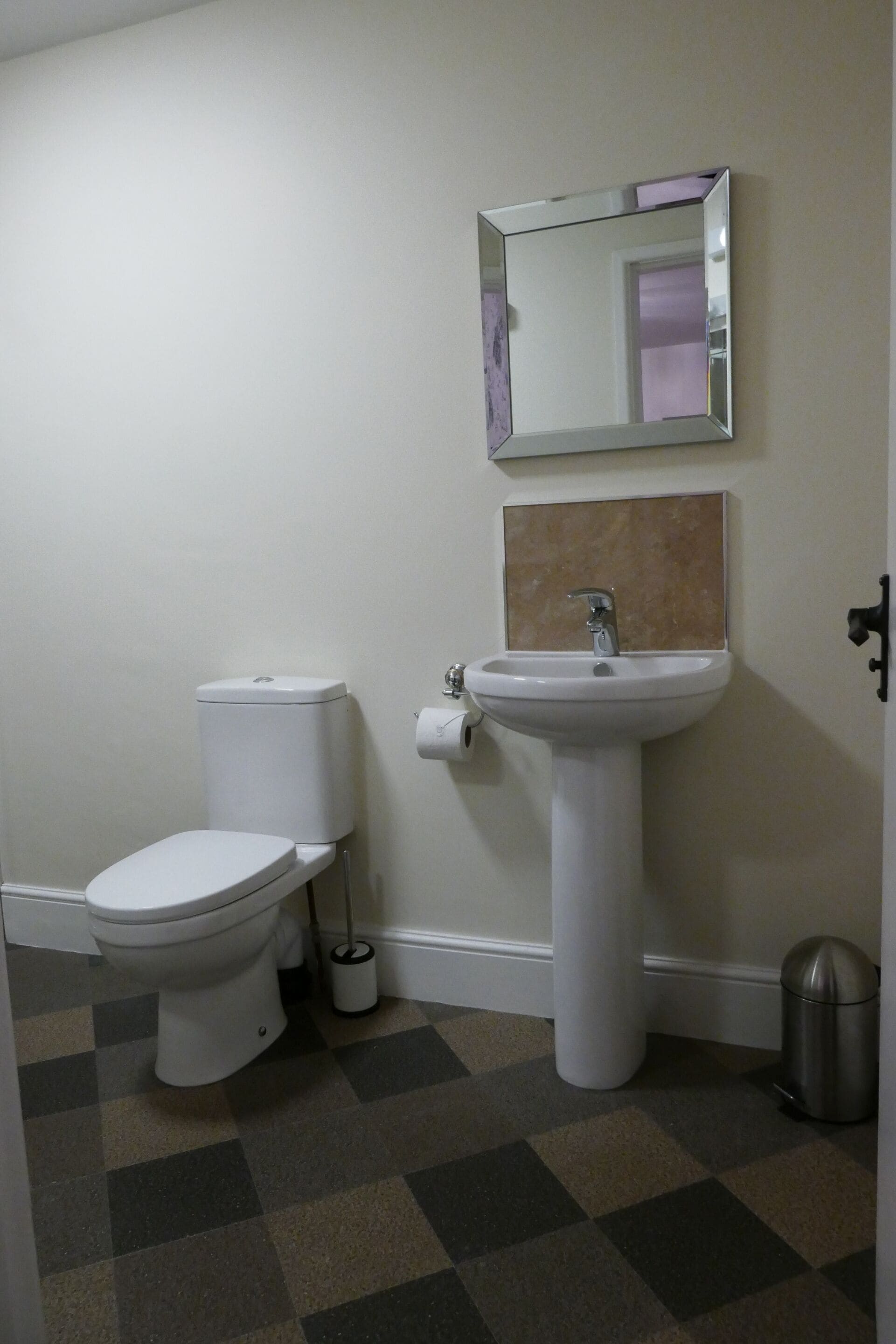 Een badkamer met toilet, wastafel en spiegel.