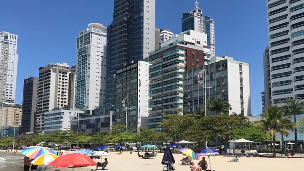 Ein Strand mit Sonnenschirmen und Menschen.