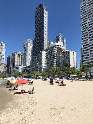 Ein Strand mit Sonnenschirmen und Menschen.