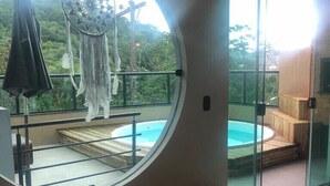 Ein Zimmer mit rundem Fenster, das Blick auf einen Pool und üppiges Grün bietet.