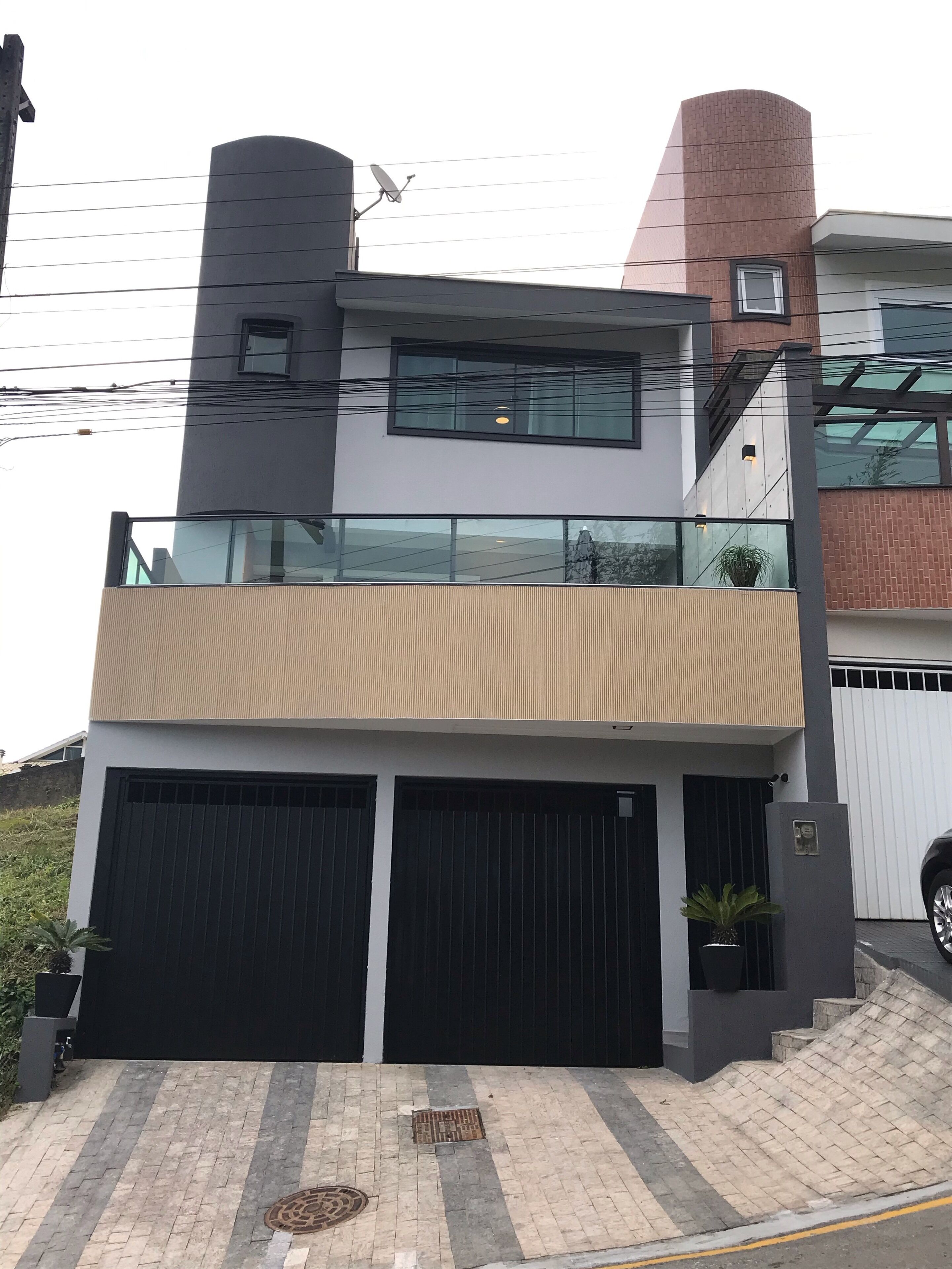 A modern two-story house with a flat roof, large windows, and a balcony.