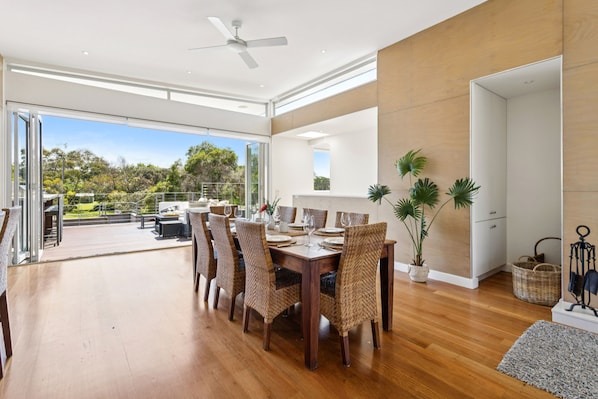 A spacious dining area with a wooden table, woven chairs, and a view of the outdoors.