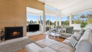 A modern living room with a fireplace, a flat-screen TV, and a sofa. - Fairway View (FLINDERS)