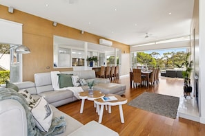 A modern living room with a sofa, coffee table, and dining area with chairs.