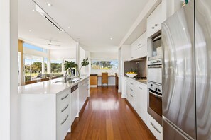 Una cocina moderna con muebles blancos, electrodomésticos de acero inoxidable y vistas al exterior.