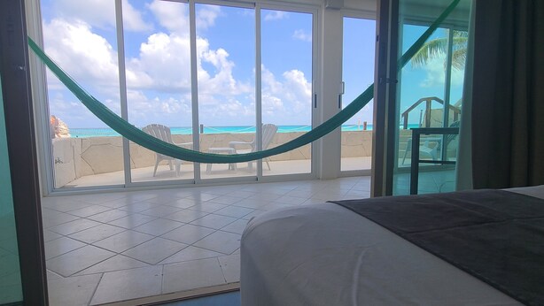 A hotel room with a large sliding glass door leading to a balcony with a view of the beach and ocean. - 2 Steps to the Beach 2 bedroom apartment (Zona Hotelera)