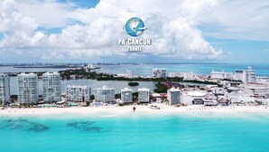 A coastal cityscape with high-rise buildings, a beach, and clear turquoise waters. - 2 Steps to the Beach 2 bedroom apartment (Zona Hotelera)