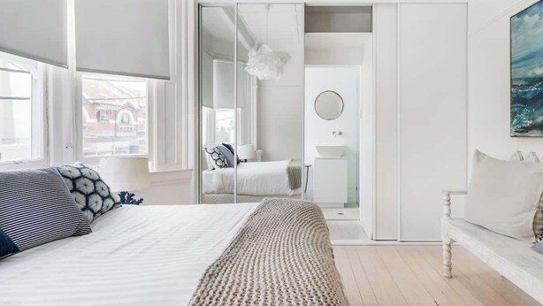 Een slaapkamer met een bed, nachtkastje en spiegel.