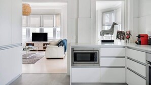 Een moderne keuken met een ingebouwde magnetron, witte kasten en een rode apparatuur op het aanrecht.