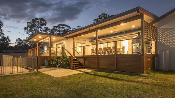 Una casa moderna con porche cubierto, una escalera y un interior bien iluminado.