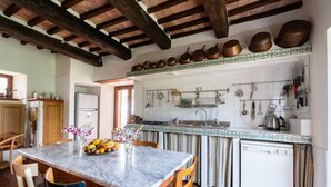 Une cuisine dotée d’un plan de travail en marbre, de chaises en bois, d’une table à manger et d’une variété d’ustensiles et d’appareils de cuisine.