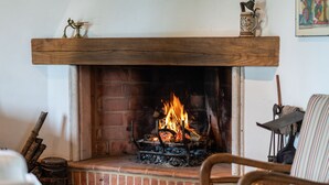 Une cheminée avec un manteau en bois, un foyer en briques et un feu qui crépite.