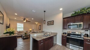 A modern kitchen with granite countertops, stainless steel appliances, and dark wooden cabinets. - Gator Cove: Quaint 2-bedroom, 1-bath cottage, sleeps 4. Great for a peaceful retreat. (Oviedo)