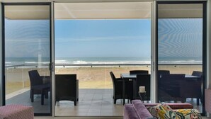 A balcony with a view of the beach, furnished with a sofa, chairs, and a table. - 52 Esplanade - Luxury - Seafront - Wi-Fi (Middleton)