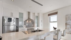 A modern kitchen with stainless steel appliances, a central island with seating, and a large window providing natural light. - 52 Esplanade - Luxury - Seafront - Wi-Fi (Middleton)