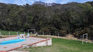 A swimming pool with a brick border and a grassy area in front. - Mini Chácara Campo Verde Ibiúna SP<br>A cozy and simple place to relax (Ibiúna)